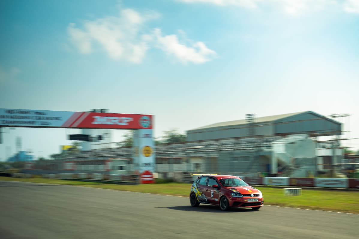 Avi's red race car carrying speed down the main straight